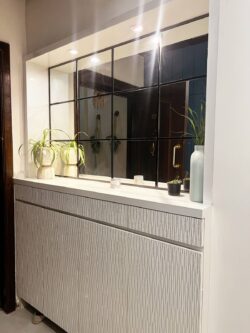 A grand and practical first impression. Elegant foyer entrance with raftor shutter storage cabinet and a large decorative wall mirror.