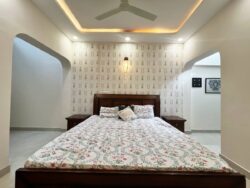 Timeless comfort meets modern elegance. An elegant parents' bedroom with a botanical feature wall and a soft curved ceiling design.